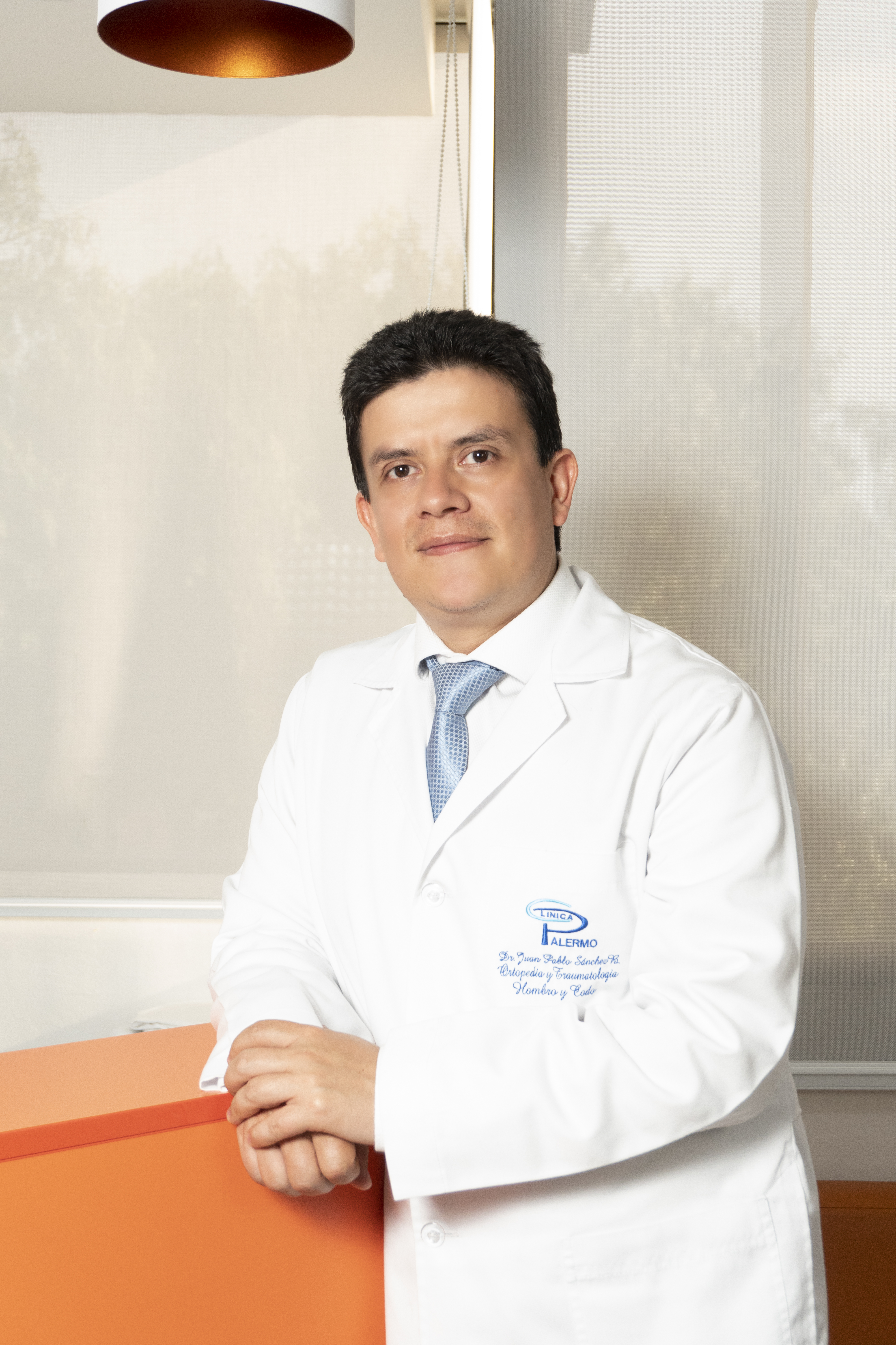 Dr. Juan Pablo Sánchez en consulta médica, revisando resonancia con paciente